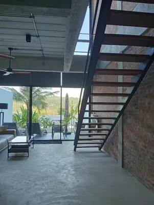 a staircase in a living room with a brick wall at Sky Lofts Phuket in Nai Yang Beach