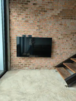 a flat screen tv mounted on a brick wall at Sky Lofts Phuket in Nai Yang Beach