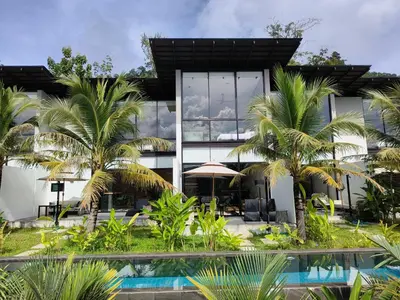 a house with a swimming pool and palm trees at Sky Lofts Phuket in Nai Yang Beach