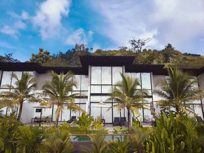 a building with palm trees in front of it at Sky Lofts Phuket in Nai Yang Beach
