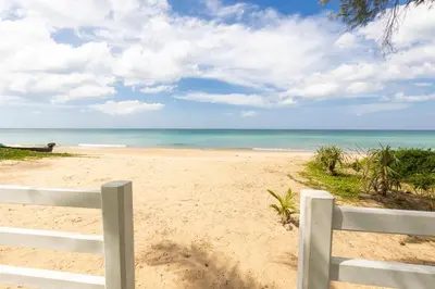 a white fence on a beach with the ocean at Carpe Diem Beach Villa in Natai Beach