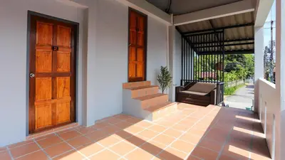 a porch of a house with a door and stairs at Bangtao Guest House in Bang Tao Beach