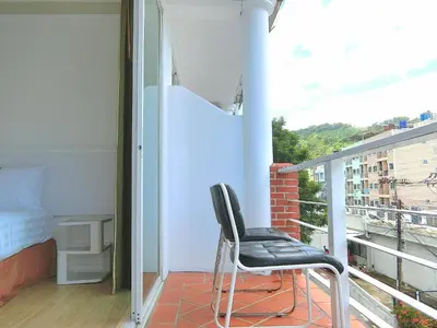 a chair sitting on a balcony with a bed at Sira Boutique, Patong in Patong Beach