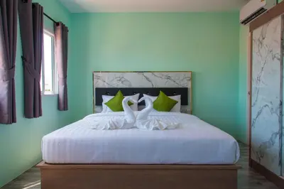 two swans sitting on a bed in a bedroom at Anatasia Apartment Phuket in Phuket Town