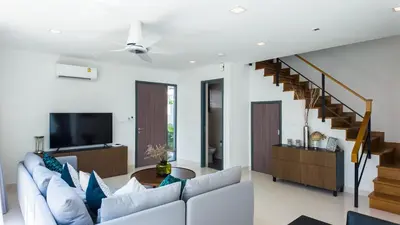 a living room with a white couch and a tv at Laguna Park Villa in Phuket Town