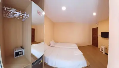 a small room with two beds and a tv at Lucky Seven Patong in Patong Beach