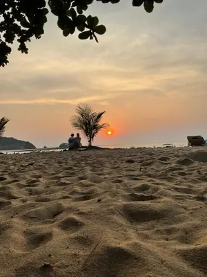 two people sitting on the beach watching the sunset at Bangreen Naiyang Hotel in Nai Yang Beach