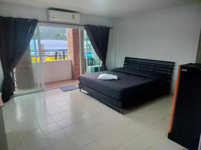 a bedroom with a black bed and a large window at the three pyramids in Phuket Town