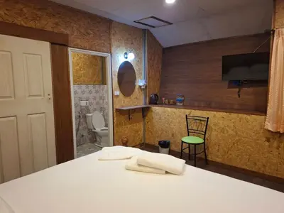 a room with a table and a bathroom with a toilet at ฟาดิลบังกะโล Fadel bungalow in Ban Lo Pa Ret