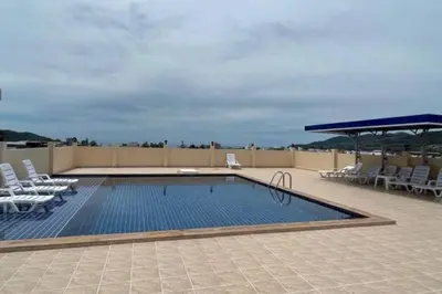 a swimming pool on a roof with chairs and a umbrella at 1 bed condo, No.1 location, next to Patong Beach. in Patong Beach