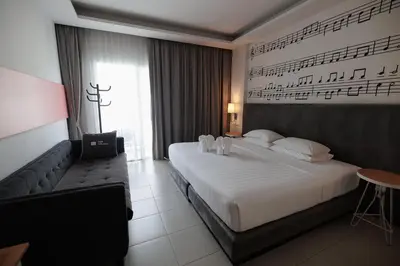 a hotel room with a large bed and music on the wall at The Melody Phuket Kata Beach in Kata Beach