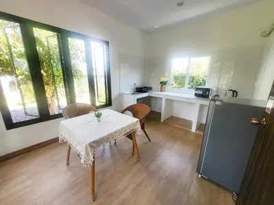 a room with a table and a kitchen with windows at Himaphan Boutique Resort - SHA EXTRA PLUS in Nai Yang Beach
