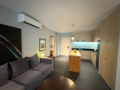 a living room with a couch and a kitchen at Studio with forest view - Zen Space by Lofty in Kamala Beach