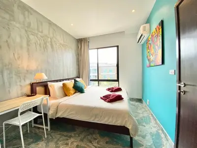 a bedroom with a bed and a table and a window at Rawai - Beachfront Apartement - The Title in Rawai Beach