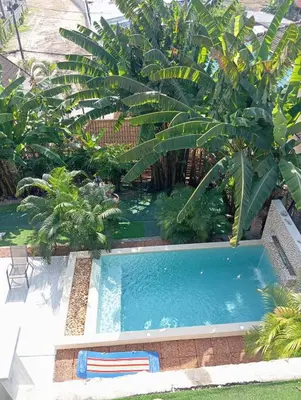 a swimming pool in a garden with palm trees at Castle Villa Phuket in Kamala Beach