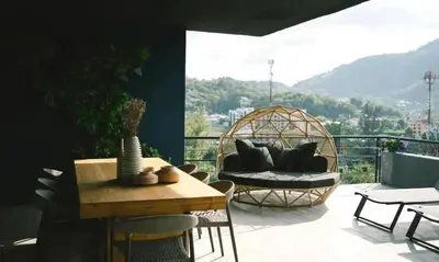 a balcony with a rattan chair and a table at Deluxe apartment Citygate Condo by Lofty in Kamala Beach