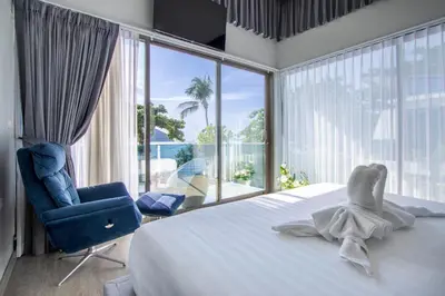 a bedroom with a bed and a chair and a large window at \u3010Beach Front\u3011\u6d77\u666f\u6c99\u6ee9\u522b\u5885\uff0c\u79c1\u4eba\u6cf3\u6c60\uff0c\u514d\u8d39\u65e9\u9910\uff0c\u5973\u4f63\u6bcf\u65e5\u6e05\u6d01\uff0c\u751f\u6d3b\u65b9\u4fbf\u4ea4\u901a\u4fbf\u5229 B in Phuket Town