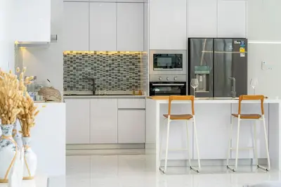 a kitchen with white cabinets and two bar stools at New Modern Aesthetic 3-Storey Villa A15 in Gated Residence just 10 min drive Laguna Phuket in Bang Tao Beach