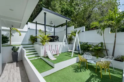 a small backyard with a slide and chairs and grass at Zen-Inspired Villa Retreat, Resort-Style Pool, Stunning Rooftop & Kid-Friendly Playground in Rawai Beach