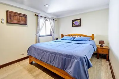 a bedroom with a bed with blue sheets and a window at Bungalow Phuket in Kamala Beach