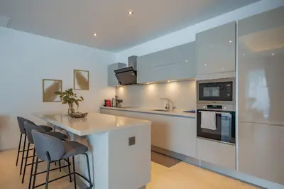 a kitchen with white cabinets and a island with bar stools at 3BR Villa with Pool at Anchan Hills in Bangtao in Bang Tao Beach