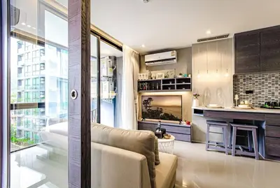 a living room with a couch and a kitchen at Citygate Condo Kamala Phuket in Kamala Beach