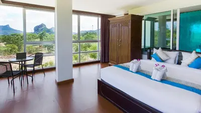 a bedroom with a large bed with a table and chairs at The Pano Hotel And Residence in Ao Nang Beach