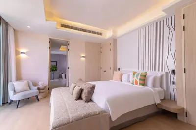 a bedroom with a large white bed and a chair at Villa Boonta in Phuket Town