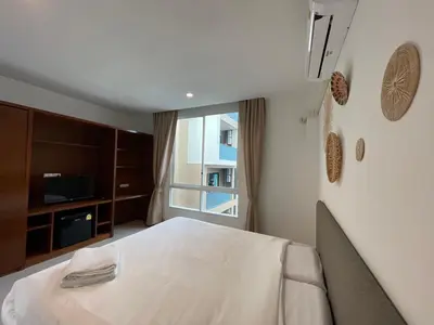 a bedroom with a white bed and a window at Chalong Inn Phuket in Ban Klang