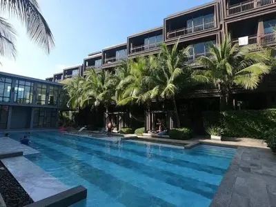 a swimming pool in front of a building with palm trees at Saturdays Residence By JJM in Ban Saiyuan (1)