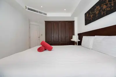 a white bed with a red pillow on it at Kata SeaView 2BR Apartment M12, just 5 min Drive from Kata Beach in Kata Beach