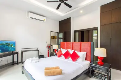 a bedroom with a large white bed with red pillows at Stylish 3BR Pool Villa Onyx H4, Gated Residence, Near Rawai & Naiharn Beach in Rawai Beach