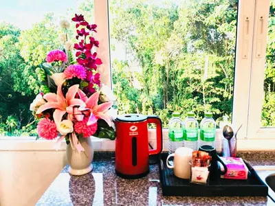 a table with a vase of flowers and a coffee mug at Siray House in Phuket Town