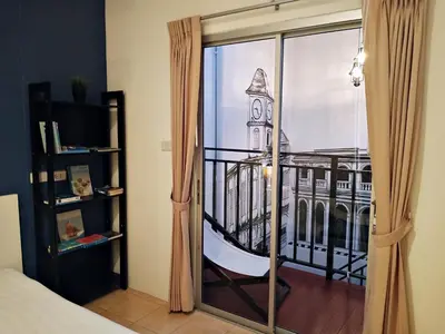 a room with a window with a view of a building at Chino Town Gallery Alley - SHA Plus in Phuket Town