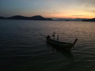 a boat sitting in the water at sunset at Large Apartment In Lovely Panwa - All Welcome! in Ban Ao Makham