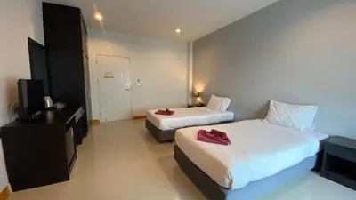 a hotel room with two beds and a television at Karon Sea Side in Karon Beach