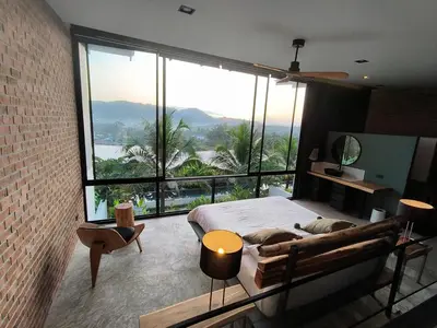 a bedroom with a bed and a large window at Sky Lofts Phuket 2 in Thalang