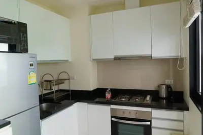 a kitchen with white cabinets and a stove top oven at Lovely Townhouse in Laguna Park in Thalang