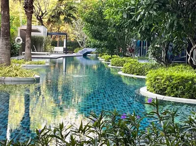 a pool in the middle of a garden with trees at Aristo Resort Surin Beach M06 in Phuket Town