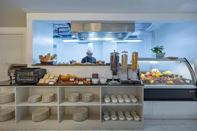 a chef in a kitchen behind a counter with food at Chateau Du Village Patong in Patong Beach