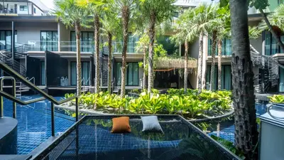 an apartment building with palm trees and a swimming pool at Luminous Resort & Spa by Areca in Phuket Town