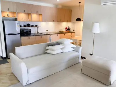a living room with a white couch and a kitchen at Appartements avec piscine in Rawai Beach