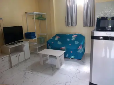a living room with a blue couch and a tv at Kathu Waterfall Bungalow Holyday home in Ban Huai Luk (1)