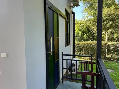 a porch with a green door and two stools at Baan Koh Kwang Pool Villa Krabi in Krabi town