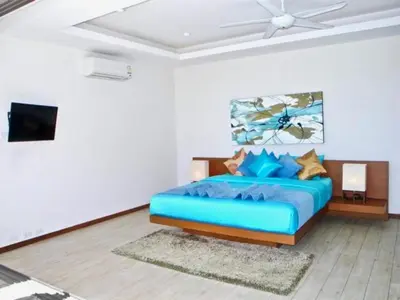 a bedroom with a blue bed and a tv at Rawai Beach Private Pool Villa -3 Bedrooms in Rawai Beach
