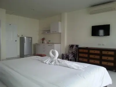 a bedroom with a white bed with a swan on it at The Green House in Kata Beach