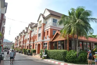 people walking down a street in front of a building at The Green House in Kata Beach