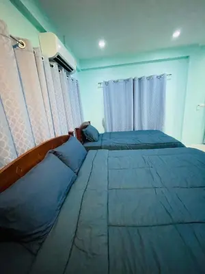 a bedroom with two beds with blue sheets and curtains at NUN GUEST HOUSE in Ban Bo Han