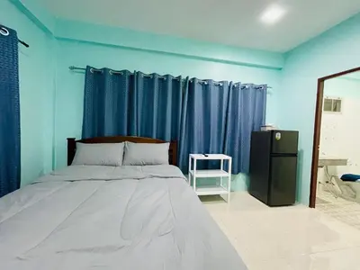 a bedroom with a bed with blue walls and blue curtains at NUN GUEST HOUSE in Ban Bo Han
