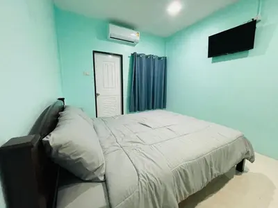 a bedroom with a bed and a tv on the wall at NUN GUEST HOUSE in Ban Bo Han